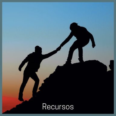 Dos personas ayudándose a escalar una montaña al atardecer.